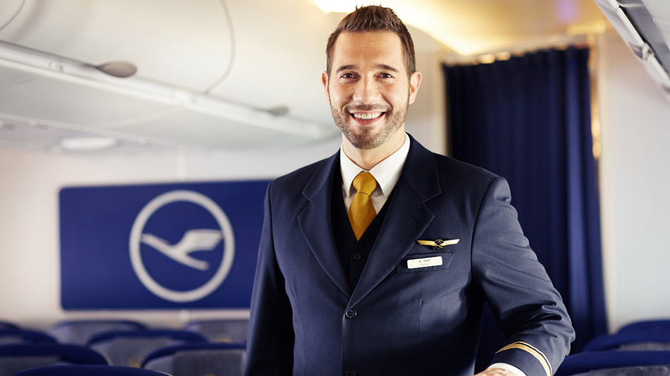 Ein lächelnder Flugbegleiter steht in einer Flugzeugkabine