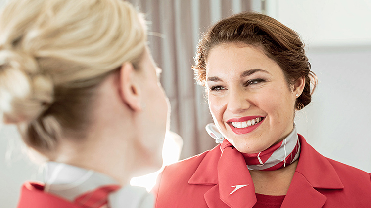 Zwei lächelnde Flugbegleiterinnen der Austrian Airlines tragen Uniform und Halstücher
