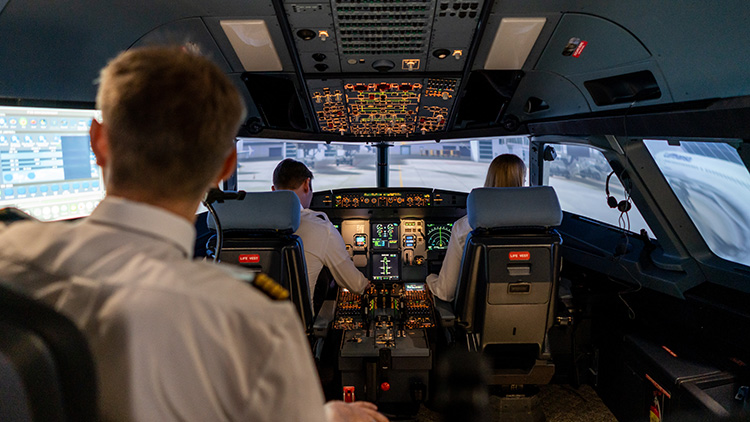 Blick in einen Cockpit-Simulator mit zwei Piloten und einem Ausbilder