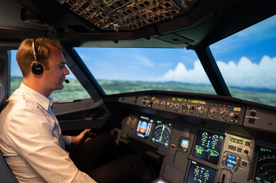 A pilot is sitting in the cockpit of a flight simulator.