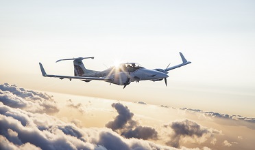 A DA42 from the European Flight Academy flies above the clouds at sunset.